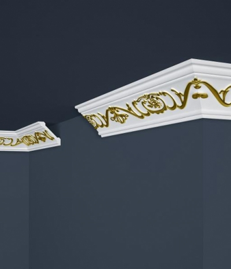 Biela stropná lišta so zlatým ornamentom.